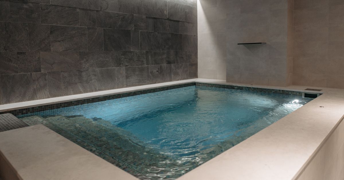 Piscina interior de spa con luz cálida y reposeras alrededor del agua