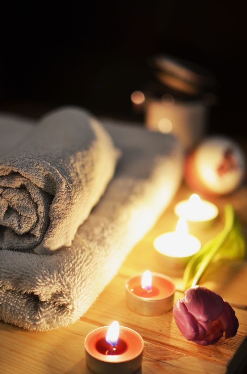 Bañera con agua, velas encendidas y toallas dobladas junto al borde